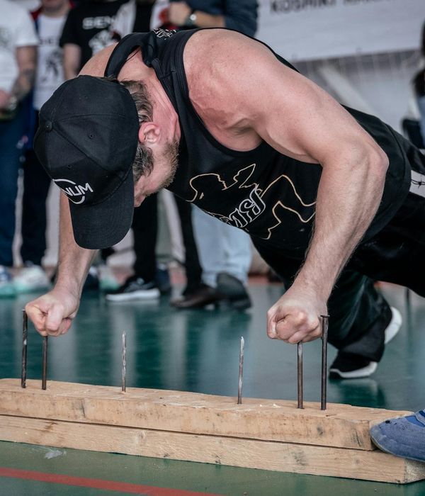 A focused man in athletic wear holding a steady pose, showing concentration and strength.